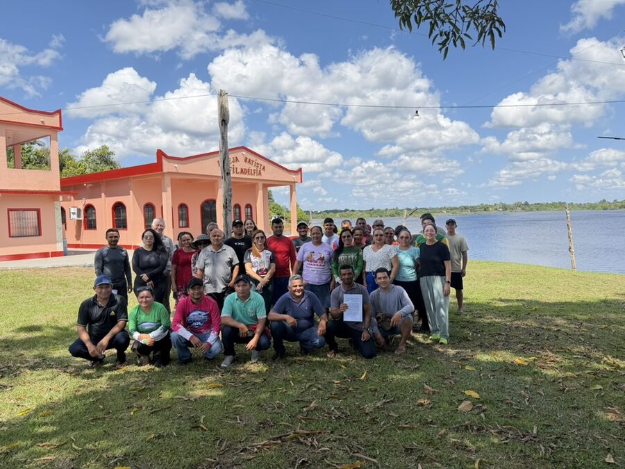 Grupo diante de uma igreja à beira do lago na comunidade Campo Novo